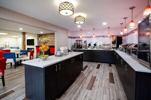 Una cocina moderna con una isla central, armarios negros y una variedad de electrodomésticos.