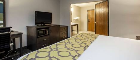 A hotel room with a bed, a TV, a microwave, and a desk with a chair.