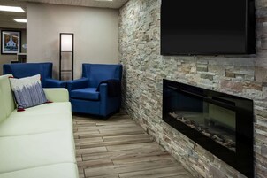 Una sala de estar con pared de piedra, un televisor de pantalla plana sobre la chimenea y dos sofás.