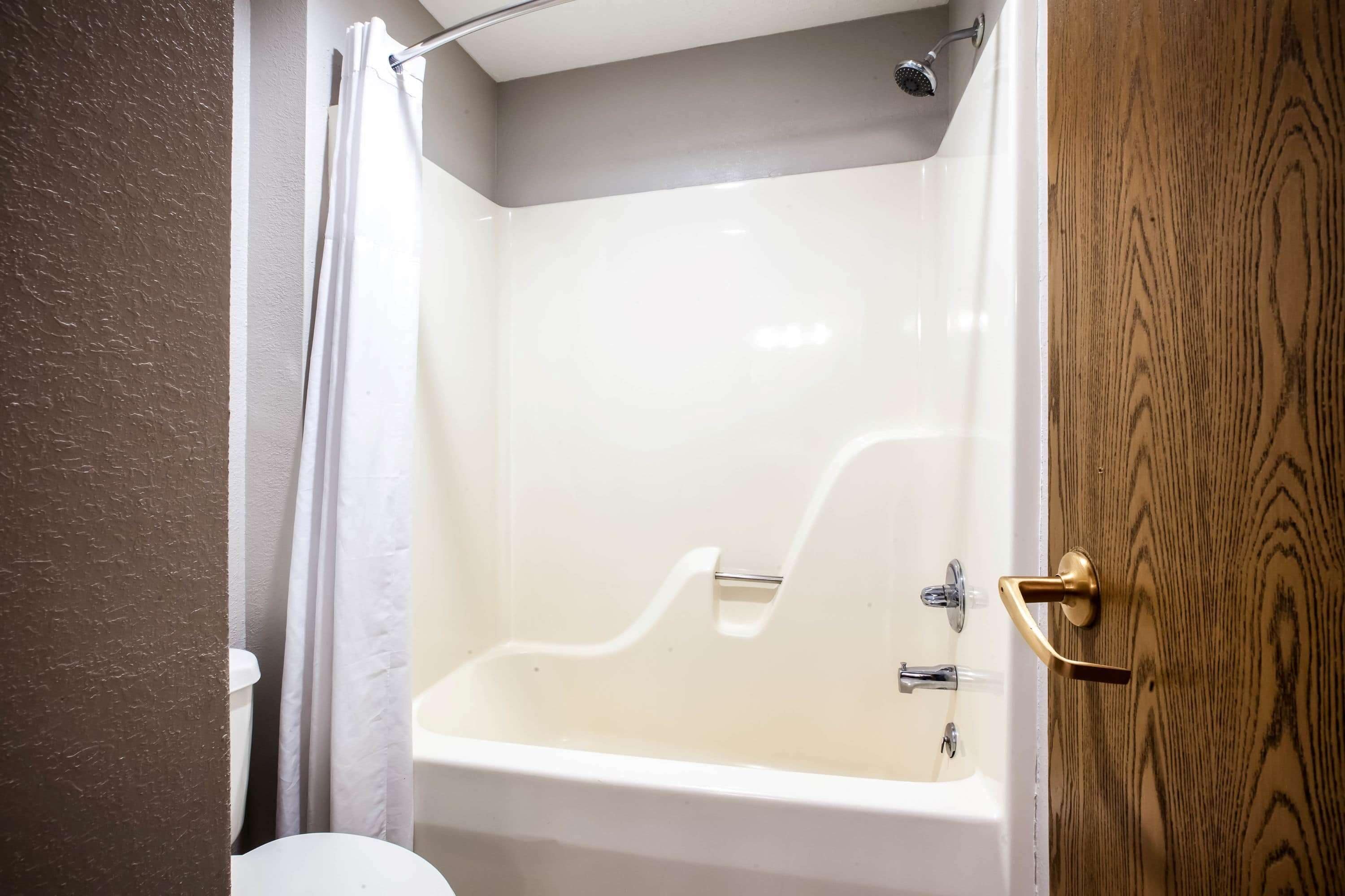 A bathroom with a bathtub, a toilet, and a shower curtain.