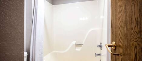 A bathroom with a bathtub, a toilet, and a shower curtain.