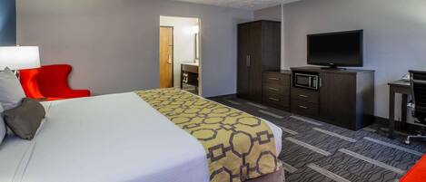 Une chambre d’hôtel avec un grand lit, un fauteuil rouge, une télévision, une armoire et un four à micro-ondes.