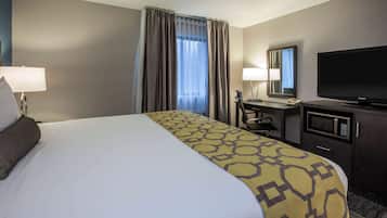 A hotel room with a large bed, a desk with a computer, a television, and a microwave.