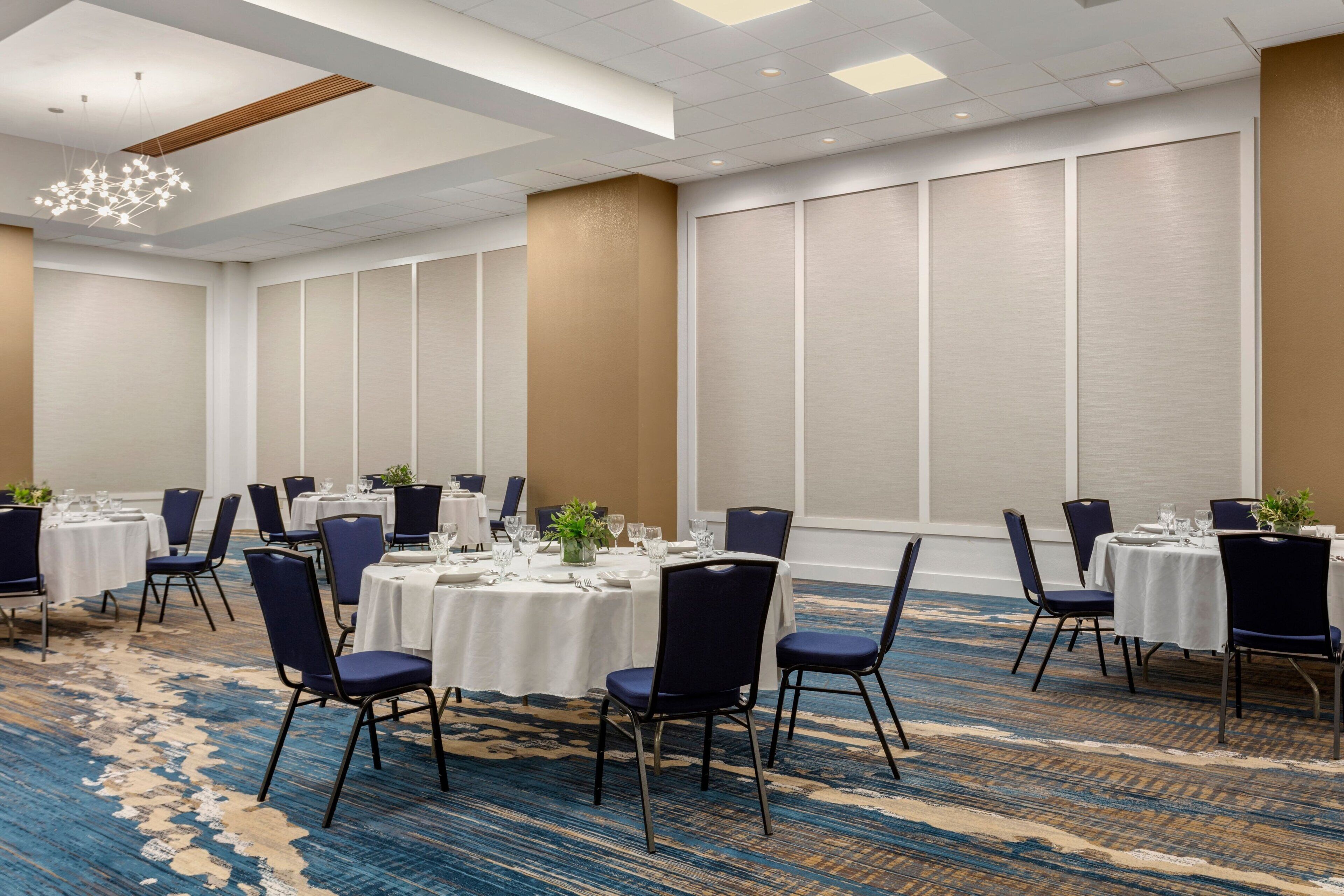 A conference room with round tables, dark blue chairs, and a blue carpet.