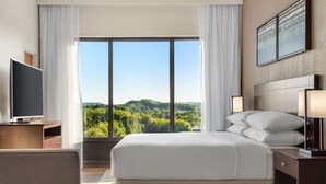 A hotel room with a large bed, a TV, a desk, and a view of a forest through the window. - Delta Hotels by Marriott Bristol (Bristol)
