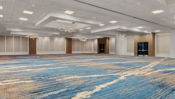 Amplia habitación de hotel con un amplio espacio alfombrado, iluminación empotrada y una lámpara de araña moderna.