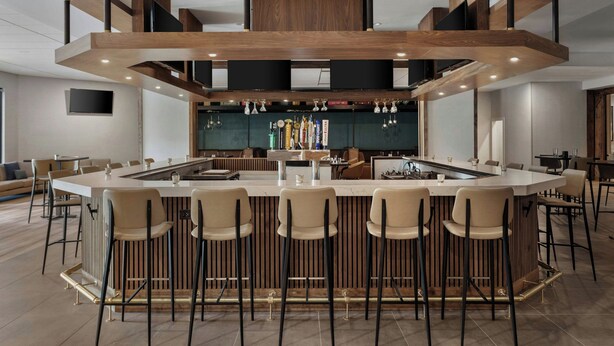 A modern bar area with a central island, bar stools, and a wooden ceiling structure. - Delta Hotels by Marriott Bristol (Bristol)