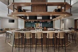 A modern bar area with a central island, bar stools, and a wooden ceiling structure. - Delta Hotels by Marriott Bristol (Bristol)