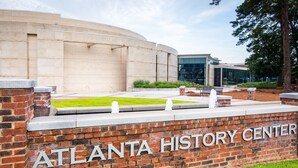 Le centre d’histoire d’Atlanta, avec un mur de briques et une enseigne, une zone herbeuse et un bâtiment moderne en arrière-plan.