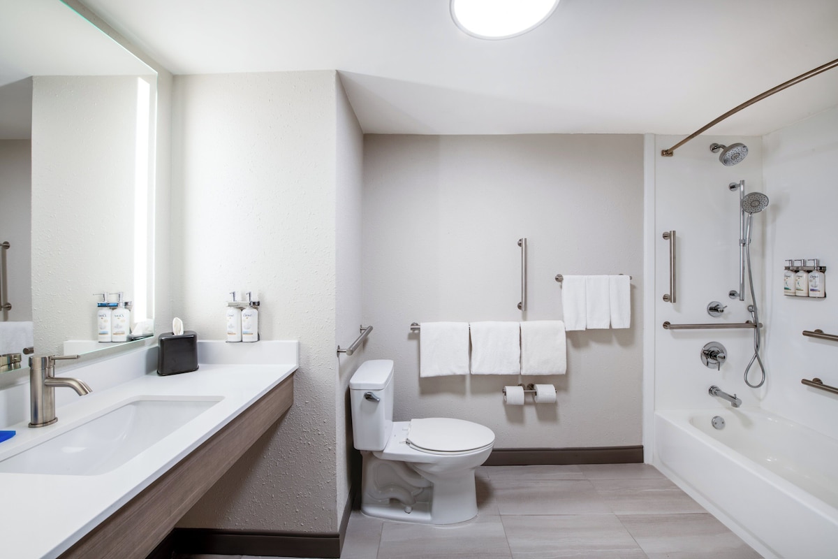 A modern bathroom with a sink, toilet, and bathtub.