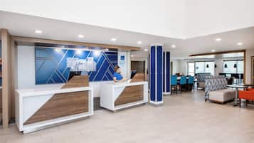 A modern reception area with two counters, a seating area with tables and chairs, and a large window providing natural light.