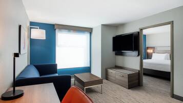 A hotel room with a bed, a desk, a chair, a TV, and a window with a view.