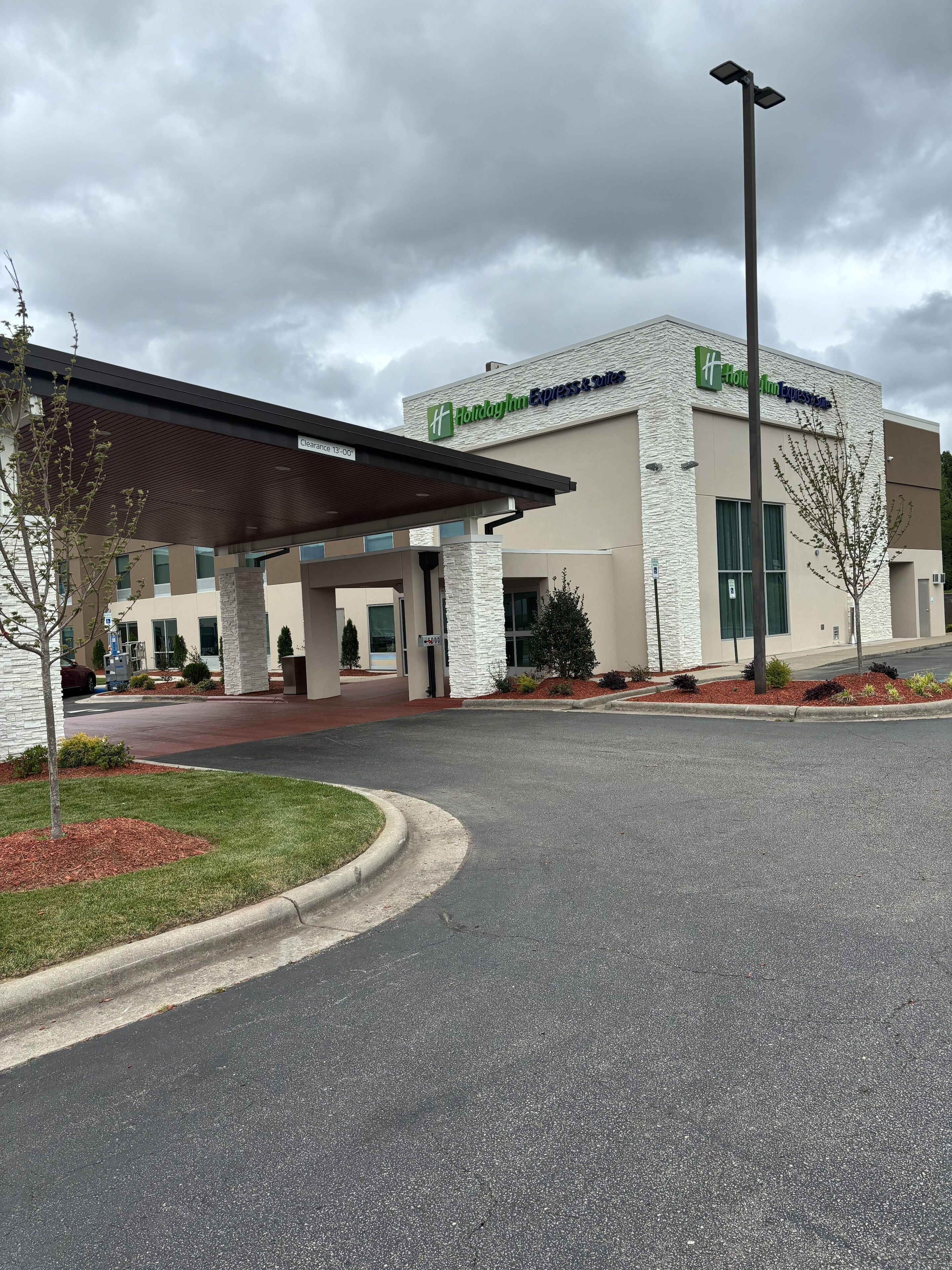 A Holiday Inn Express Suites building with a covered entrance, clear signage, and landscaped surroundings.