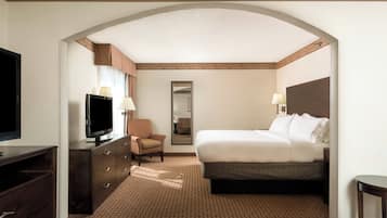 A hotel room with a bed, a television, a chair, a dresser, and a mirror.