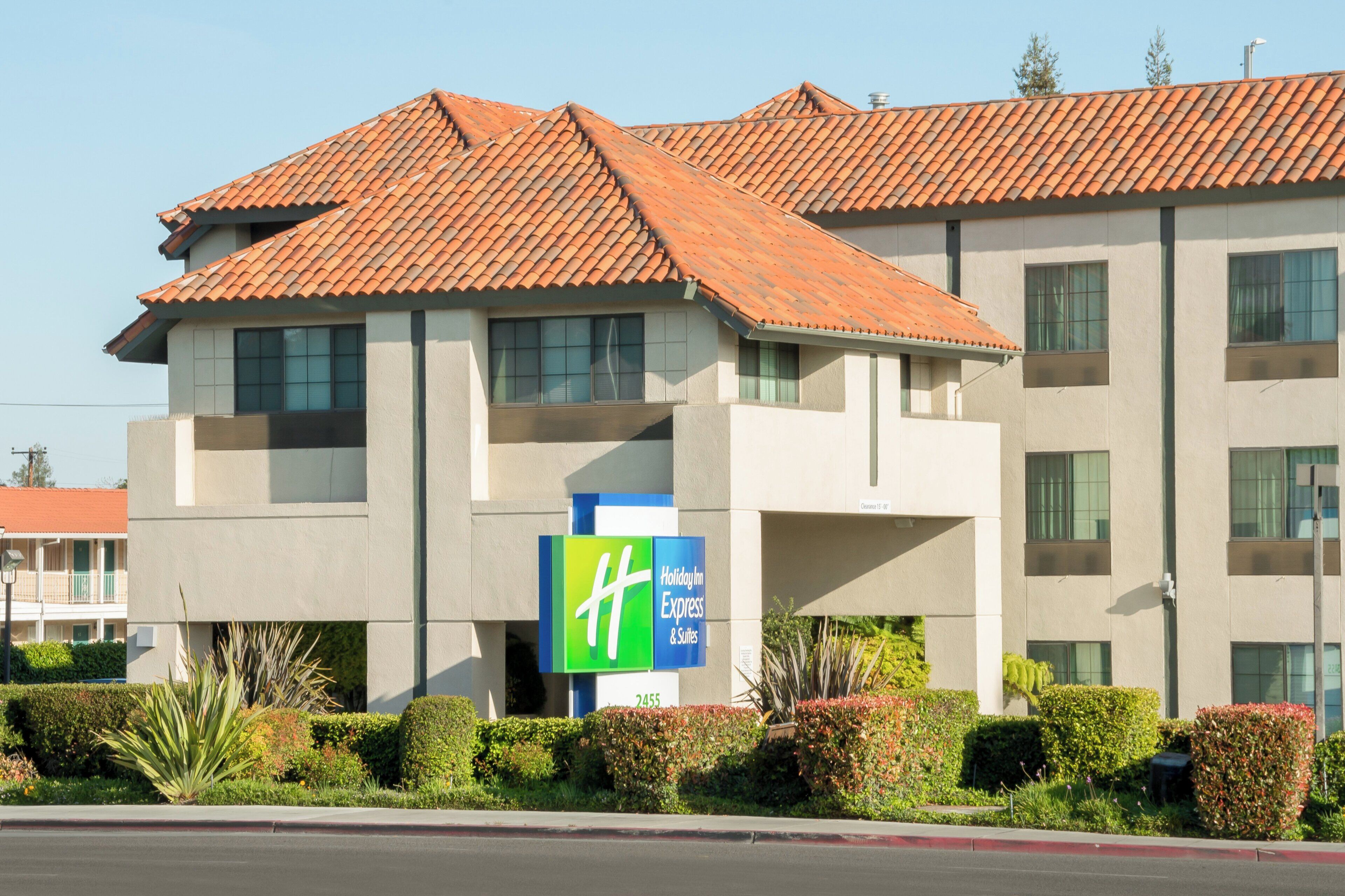 A Holiday Inn Express & Suites building with a tiled roof, multiple windows, and a sign indicating the property name.