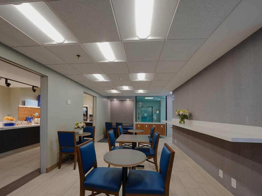 A modern dining area with round tables and blue chairs, a counter with food items, and a reception desk.