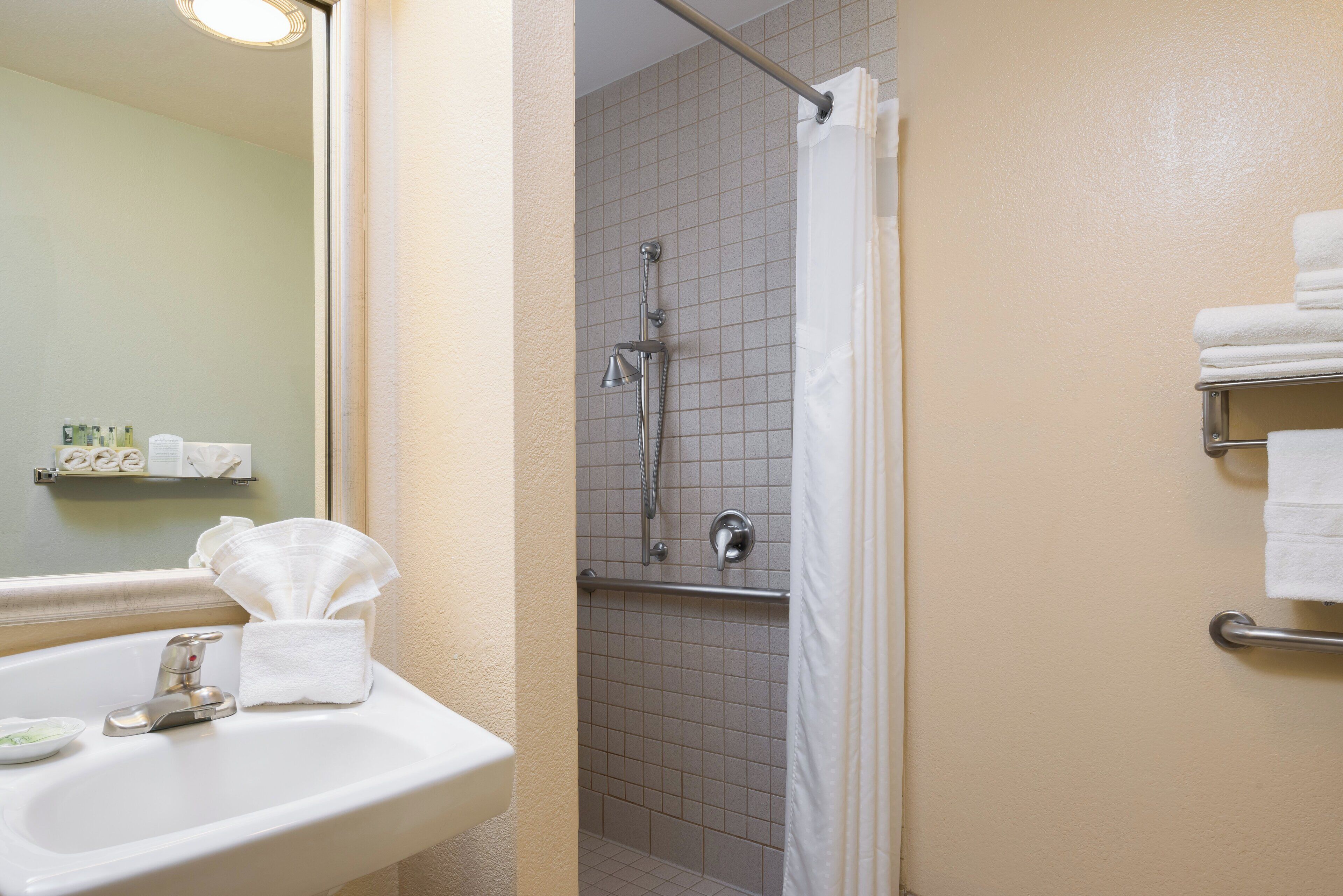 A bathroom with a sink, mirror, and a shower area with a curtain.