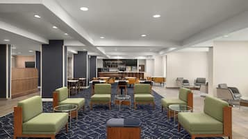 Eine Hotte lobby mit einer zentralen Sitzecke, einer Bar und einem Empfangsbereich.