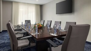 A conference room with a long table, chairs, water bottles, and a flower arrangement. - Courtyard by Marriott Beckley (Beckley)
