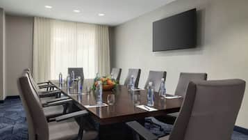A conference room with a long table, chairs, water bottles, and a flower arrangement.