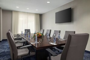 A conference room with a long table, chairs, water bottles, and a flower arrangement. - Courtyard by Marriott Beckley (Beckley)