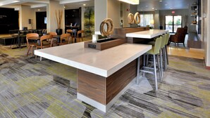 A modern hotel lobby with a central reception desk, seating area, and a large window providing natural light. - Courtyard by Marriott Beckley (Beckley)