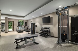 A modern gym with treadmills, weight machines, and a dumbbell rack.