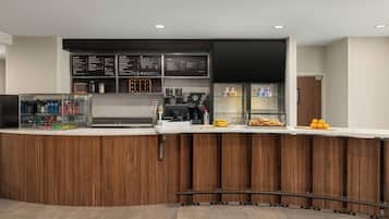 A modern bar area with a wooden counter, menu boards, and a coffee machine.