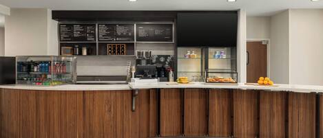 Un área de bar moderna con mostrador de madera, pizarras con la carta y una máquina de café.
