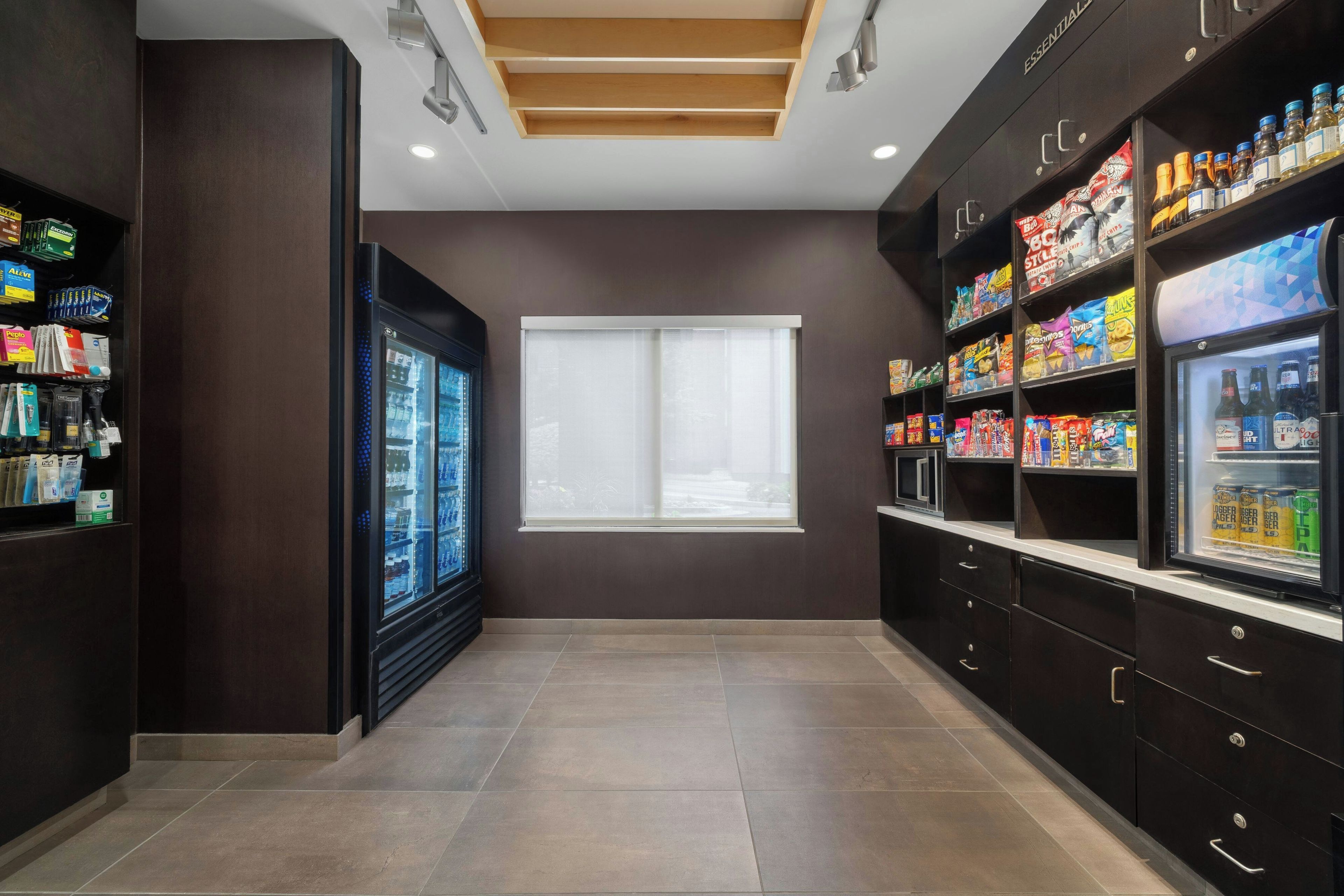 Una kitchenette moderna con refrigerador, microondas y despensa provista de bocadillos y bebidas.