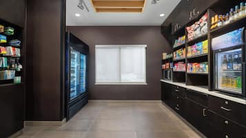 Una kitchenette moderna con refrigerador, microondas y despensa provista de bocadillos y bebidas.