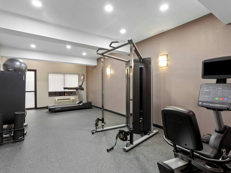 Een fitnessruimte met trainingsapparatuur, een loopband en een televisie aan de muur.