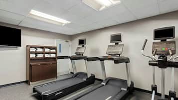 A fitness room with treadmills, a stationary bike, and a wall-mounted TV.