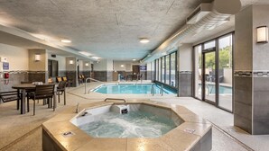 Ein Wellnessbereich mit Whirlpool, Pool und einer Sitzgelegenheit mit Tischen und Stühlen.