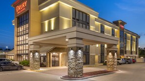 Ein Drury Inn & Suites Hotel mit modernem Design, das eine markante Eingangshalle und Säulen aus Stein zeigt.