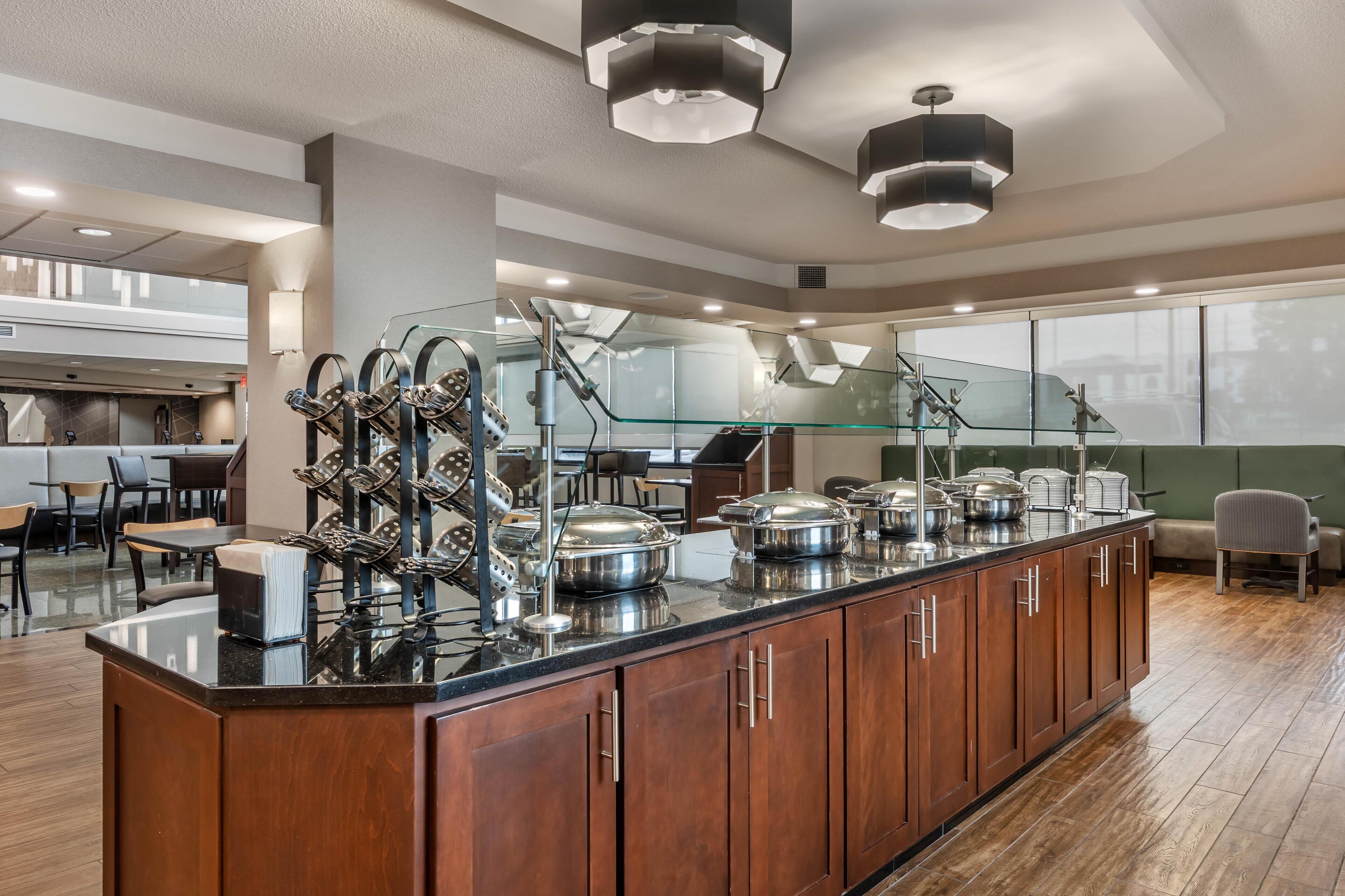 A modern kitchen area with a central island, stainless steel appliances, and a glass partition.