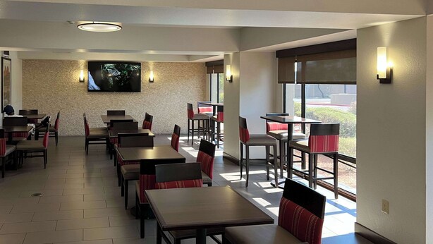 Un restaurant avec des tables et des banquettes, un téléviseur à écran plat fixé au mur et une vue sur l’extérieur.
