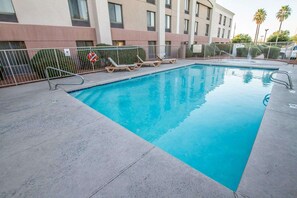 Una piscina al aire libre, sillones reclinables de piscina
