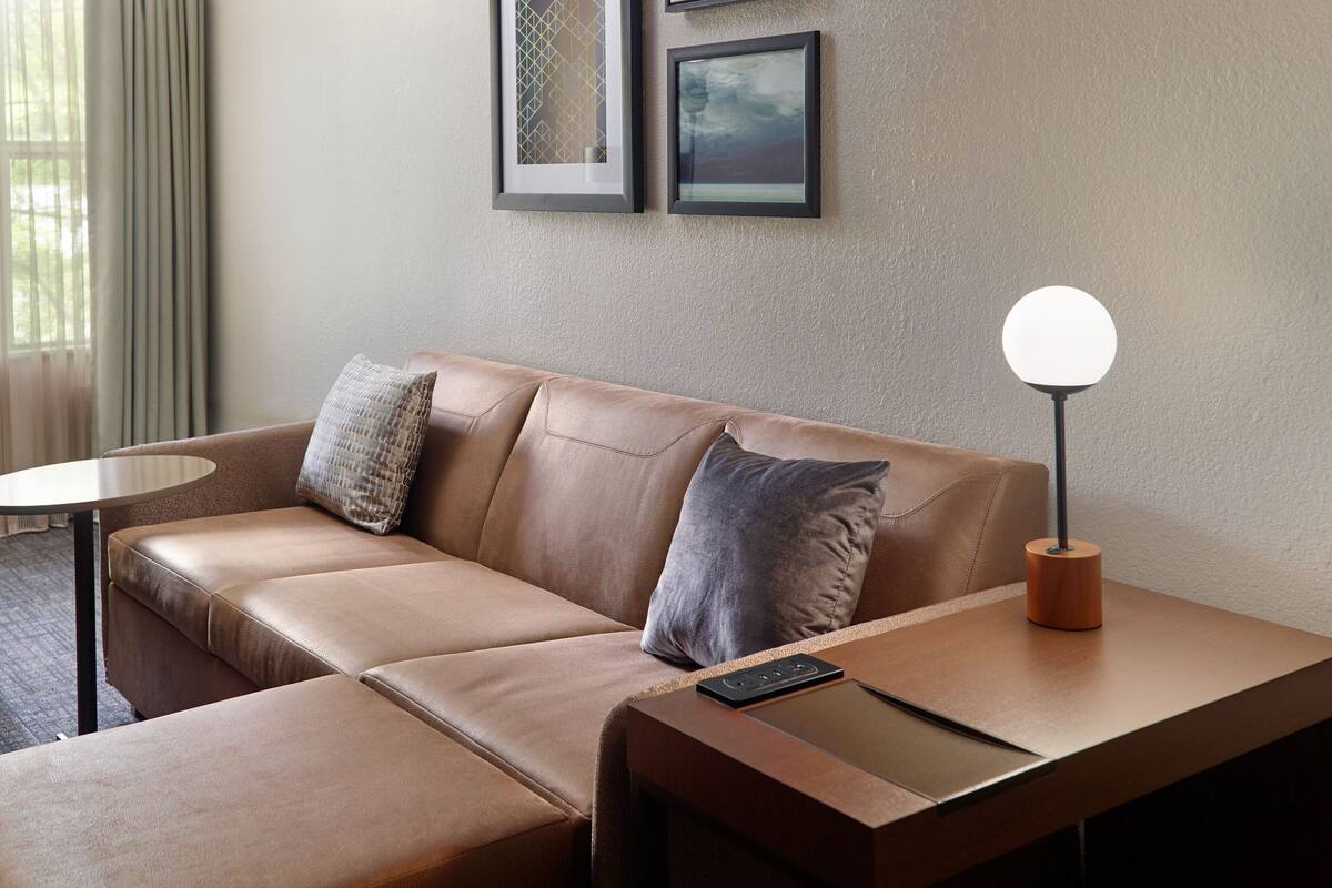 Un salón moderno con un sofá de cuero, una mesita redonda y una lámpara de pie.