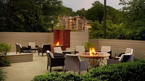 Un patio al aire libre con un pozo de fuego, una zona de estar y vistas a un edificio en el fondo.