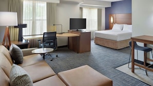 Una habitación de hotel con cama, escritorio con televisor, sofá y sillón.
