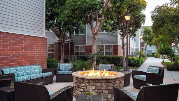 An outdoor seating area with wicker furniture and a central fire pit.