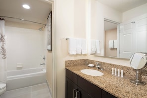 A bathroom with a bathtub, a sink with a mirror, and a toilet.
