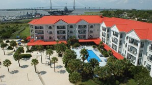 Un hotel de varios pisos con techo rojo, piscina y zona de playa.