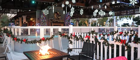 Ein Terrassenbereich im Freien mit Feuerstelle, weißem Ziergartenzaun und Weihnachtsdekorationen.