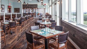 Un restaurante espacioso con techos altos, vigas a la vista y amplias ventanas que ofrecen vistas al exterior.