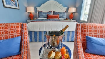 A hotel room with a bed, two bedside tables with lamps, a tray with breakfast items, and a large window with curtains.