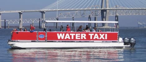 Um táxi aquático com design vermelho e branco, identificado com a inscrição “WATER TAXI”, e passageiros a bordo.