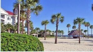 Una playa con palmeras, una estructura de techo de paja y un edificio con tejado rojo.