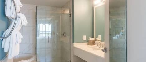 Une salle de bain moderne avec une douche à parois de verre, un lavabo blanc et un grand miroir.